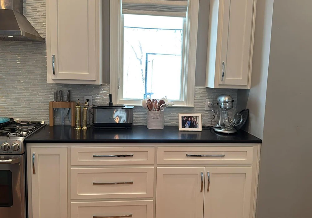 Clean kitchen with white cabinets and dark countertop